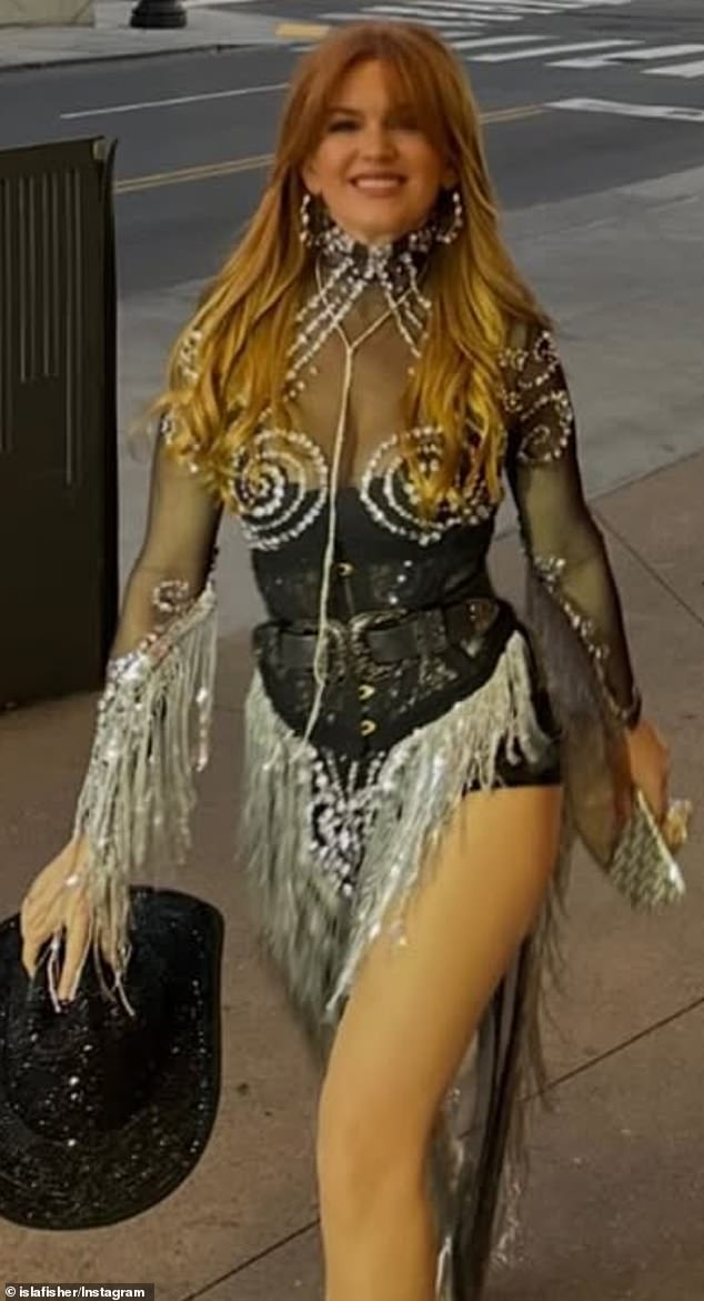 Isla Fisher confidently struts down the street holding a black sequinned cowboy hat