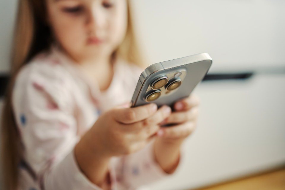 Young girl holding a smartphone, focused on technology.