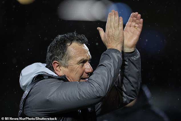 Oldham manager Micky Mellon applauds the fans on a filthy evening at Boundary Park