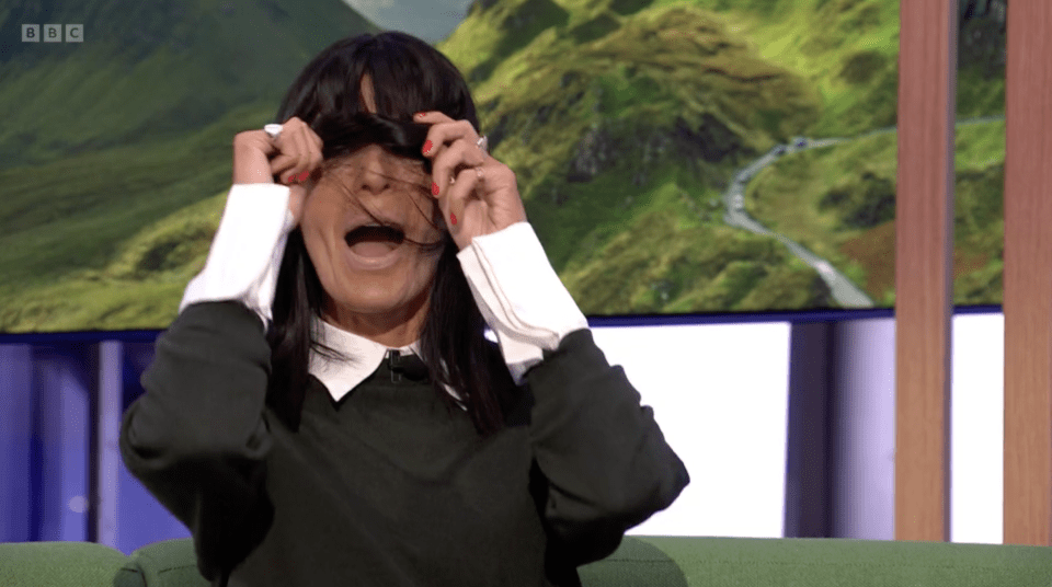 Claudia Winkleman covers her face with her hair, appearing to scream.