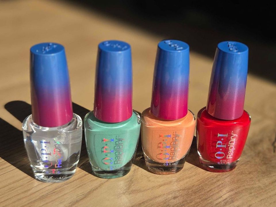 Four OPI Rapidry nail polish bottles in clear, green, orange, and red.