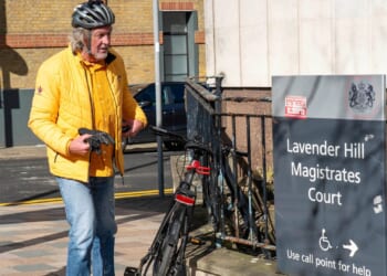 Ex-Top Gear star James May chains up his bike outside court where he was due to appear on motoring charge