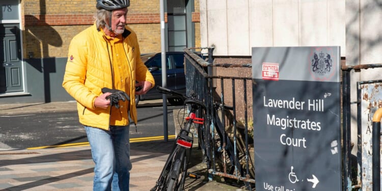 Ex-Top Gear star James May chains up his bike outside court where he was due to appear on motoring charge