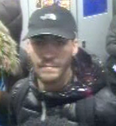 A man wearing a black baseball cap and a dark puffer jacket.