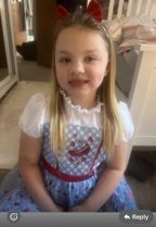 A young girl with long blonde hair and red bows in her hair, wearing a white and blue dress.