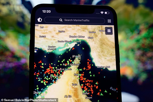 A smartphone screen displaying the MarineTraffic map shows a high concentration of ship beacons in the Strait of Hormuz in Creteil, France, on March 27, 2026