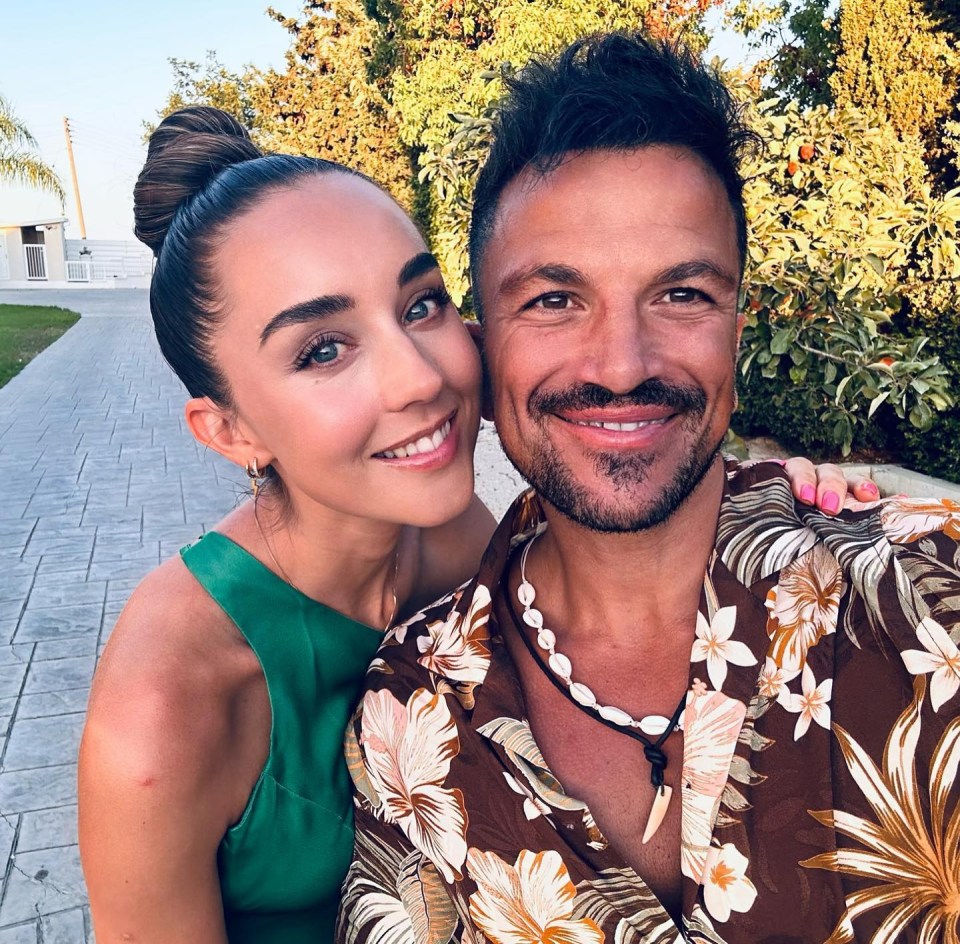Emily and Peter Andre smiling for a selfie outdoors.