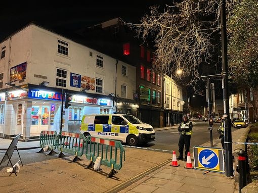 Police van and officers blocking off a street at night.