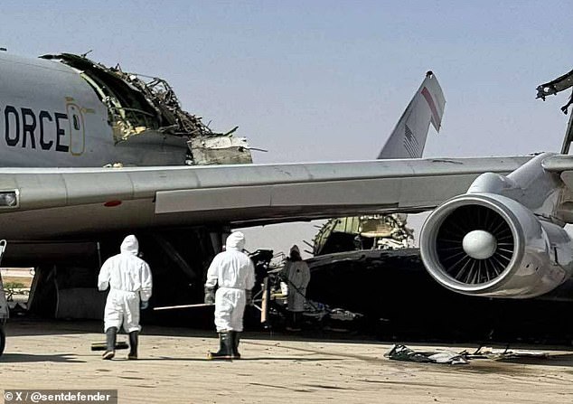 Personnel in protective suits inspect a heavily damaged aircraft, its radar section ripped apart in what appears to be a targeted strike on critical systems