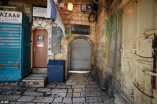 Pictured: A closed door of the Church of the Holy Sepulchre stands next to shuttered shops in Jerusalem's Old City