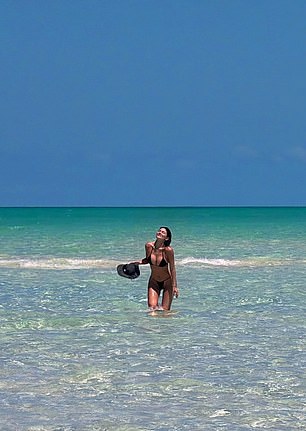 The fashionista held a floppy black sun hat