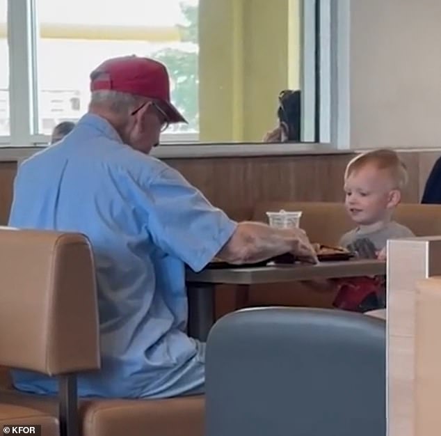 The little boy saw the man eating alone and decided to keep him company while they ate their breakfast together