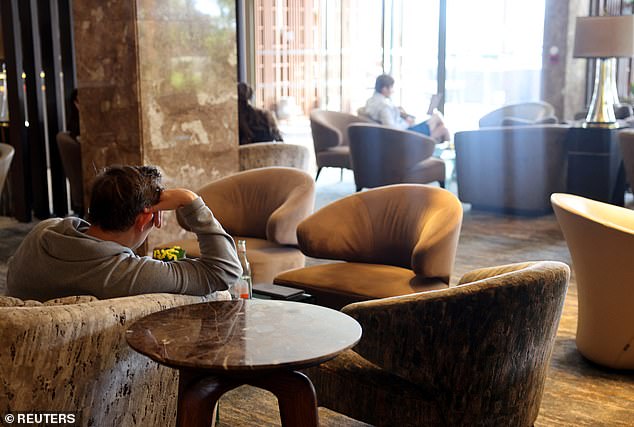 People sit in a deserted cafe in a hotel in Limassol, as booking numbers have plummeted