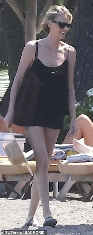 Here she is seen in her cute black minidress while walking on the sand in slip-on sandals