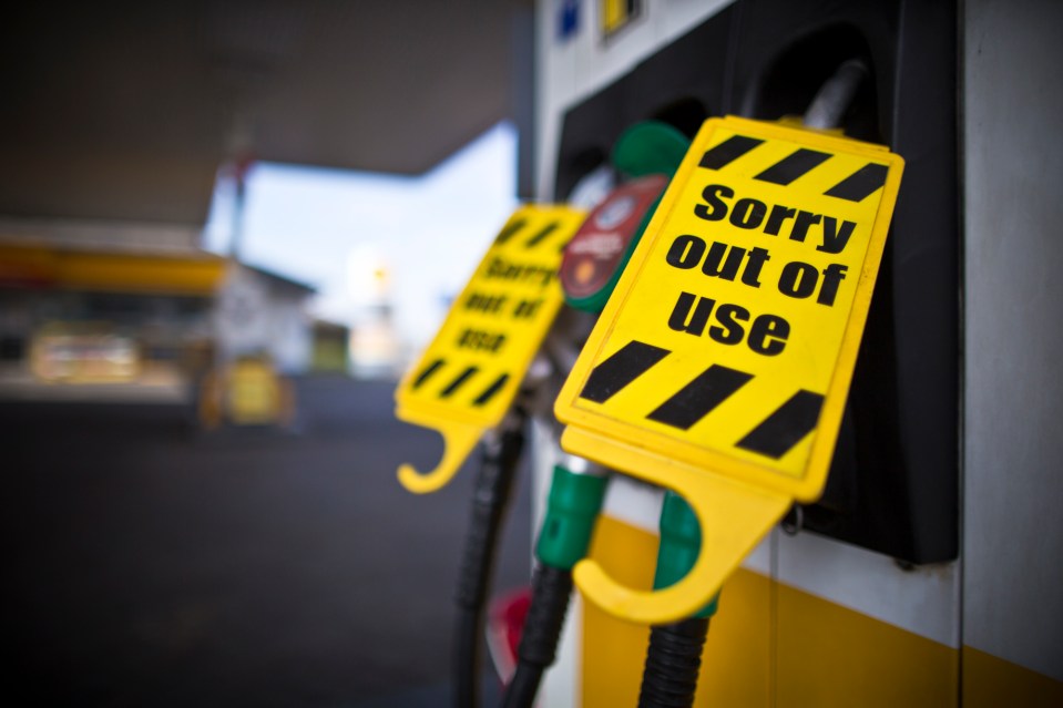 Close-up of a fuel pump at a Shell petrol station with a yellow "Sorry out of use" sign attached to the nozzle.