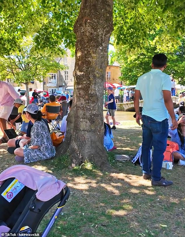 Footage posted on TikTok shows the grass verges on either side of River Windrush completely flooded with tourists snapping photos or sitting down to enjoy a picnic