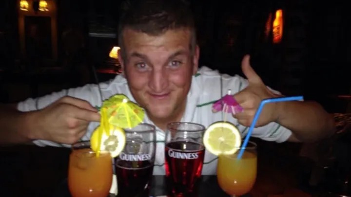A man behind a bar with three drinks and a thumbs-up.