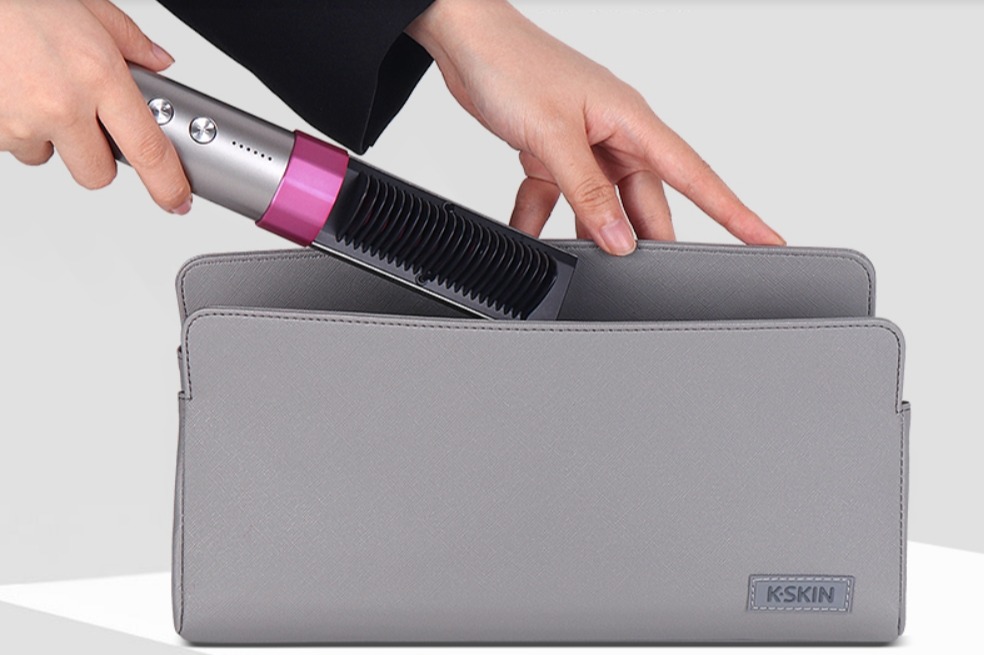 A person putting a K-SKIN portable hair straightener into a grey carrying case.