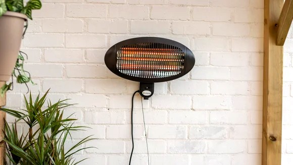 Outdoor patio heater mounted on a white brick wall.