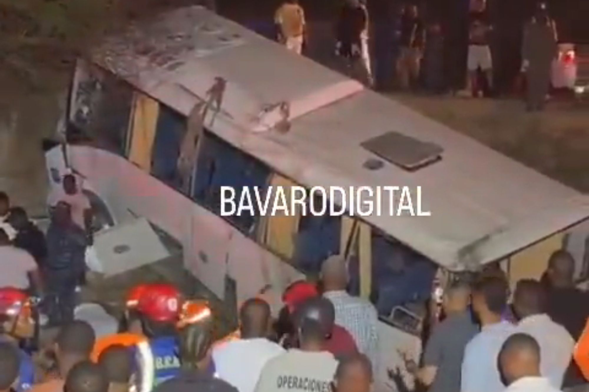 An image collage containing 1 images, Image 1 shows People gathered around a white passenger bus that crashed and lies on its side at night