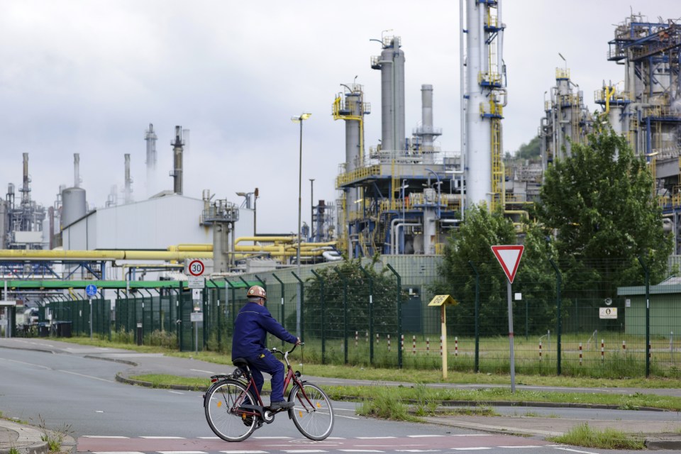 A worker on a bicycle approaches an entrance gate to the Ruhr oil refinery in Gelsenkirchen, Germany.