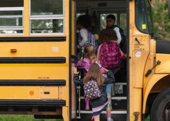 A group of elementary age children getting on a school bus.