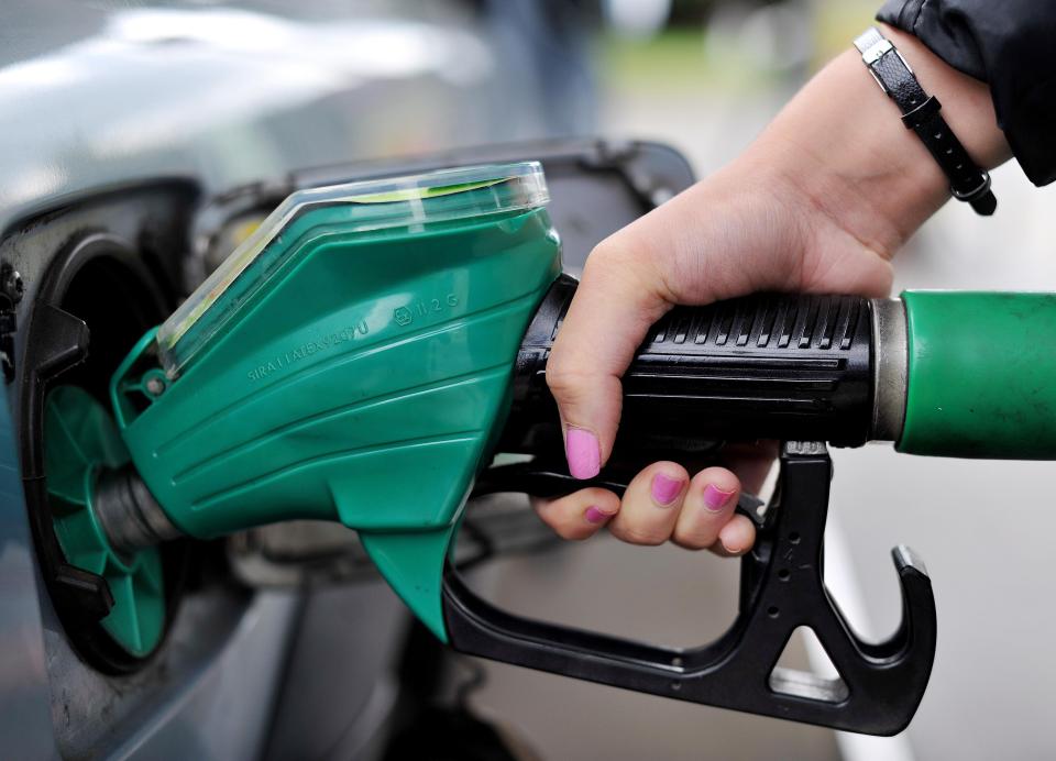 A person's hand with pink nail polish holding an Asda petrol pump nozzle in a car's fuel tank in Chelmsford, Essex.