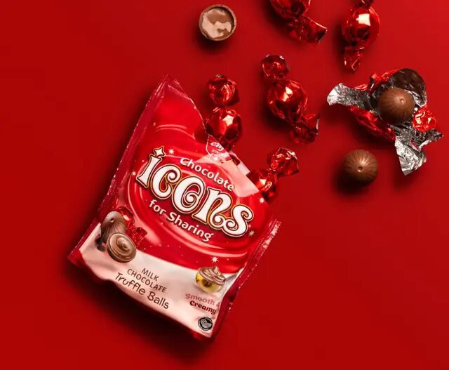 A red package of "Icons Chocolate for Sharing Milk Chocolate Truffle Balls" with several unwrapped and wrapped chocolate truffles scattered on a red background.