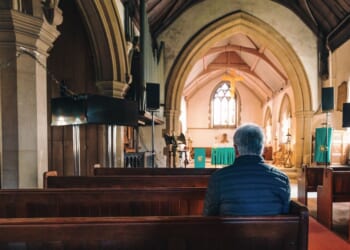 A man sitting in the pews of an Anglican Church.