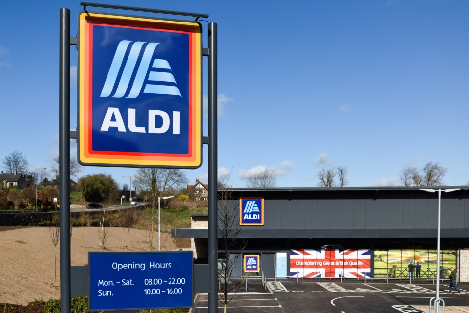 Exterior of an Aldi supermarket in Bakewell, Derbyshire, UK, with a large Aldi sign in the foreground displaying opening hours.