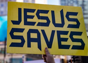 A close up of a yellow sign that says "Jesus saves."