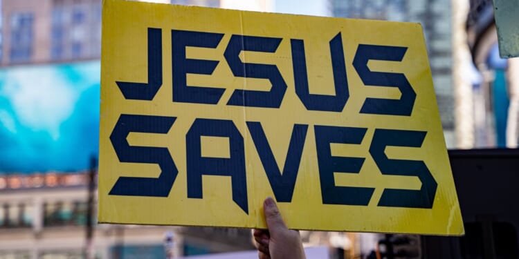 A close up of a yellow sign that says "Jesus saves."