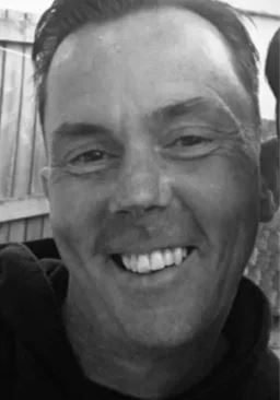 A black and white close-up photo of a man smiling.