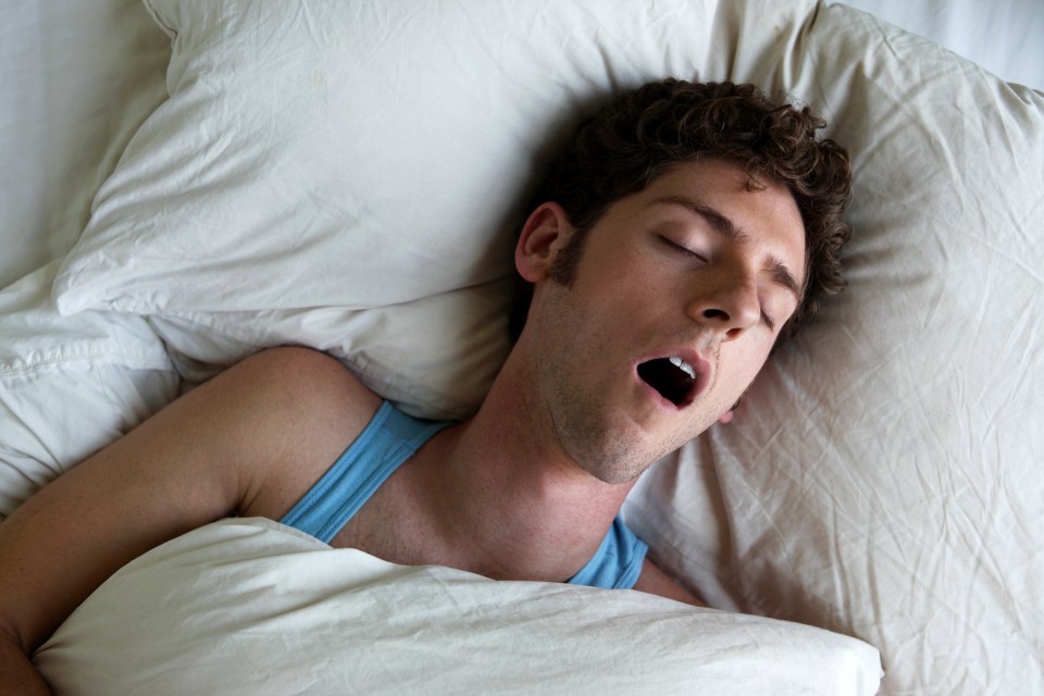 Overhead view of a young man snoring in bed.