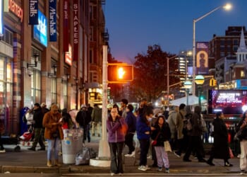 Pedestrians at a crosswalk at night of 125th Street in Harlem, New York City, on Dec. 6, 2025.