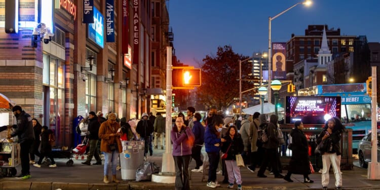 Pedestrians at a crosswalk at night of 125th Street in Harlem, New York City, on Dec. 6, 2025.
