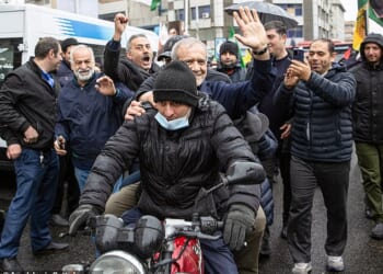 Iranian president Masoud Pezeshkian (pictured on the back of a motorcycle) waves to crowds as he attends a march in Tehran on March 13, 2026