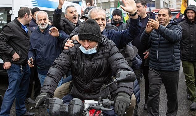 Iranian president Masoud Pezeshkian (pictured on the back of a motorcycle) waves to crowds as he attends a march in Tehran on March 13, 2026