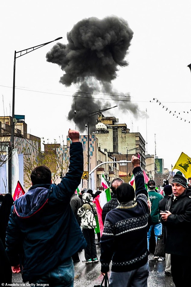 Smoke rises after an explosion during the World Quds Day march as participants carry Iranian flags and banners in Tehran, Iran on March 13, 2026