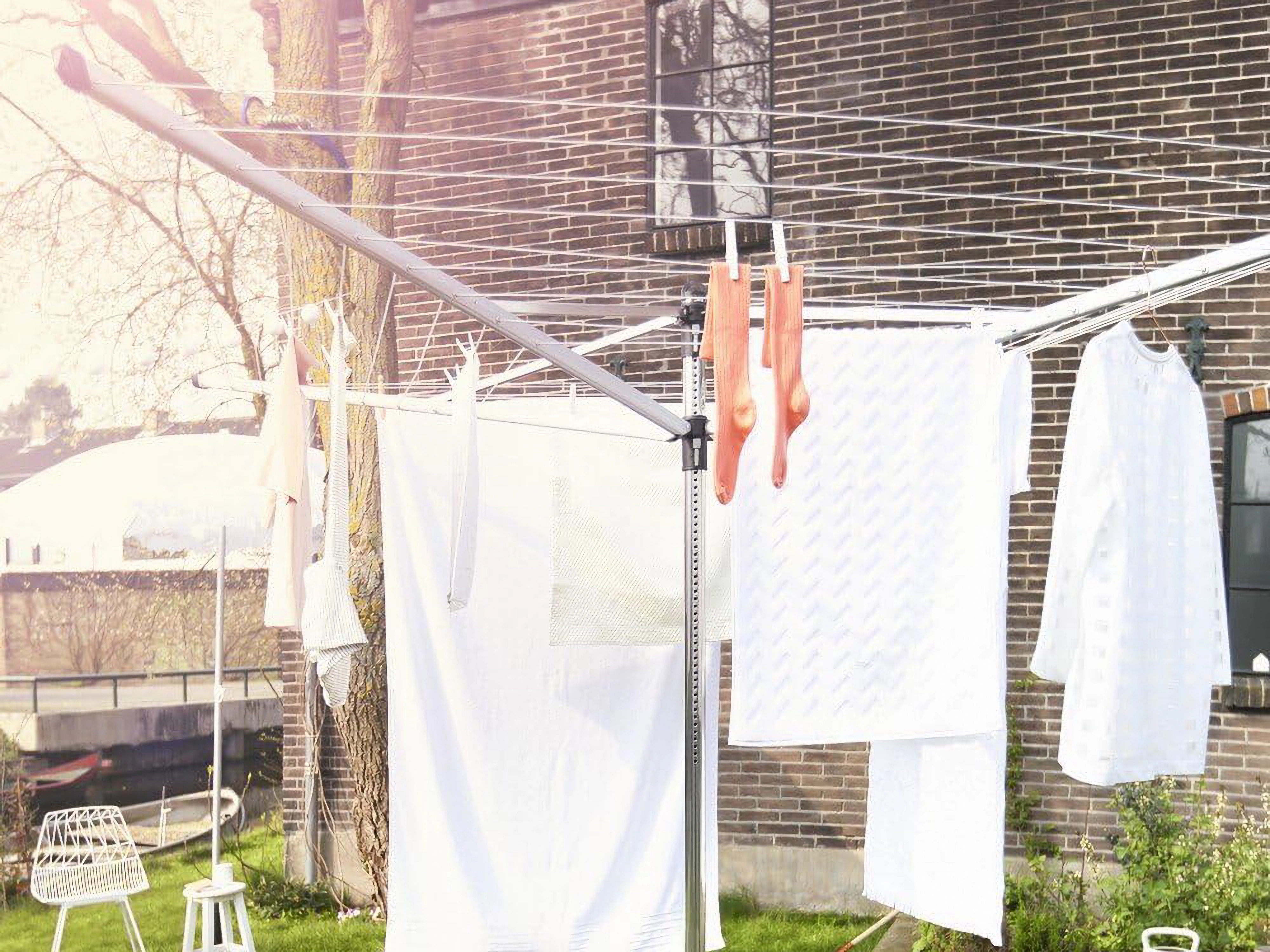 Laundry drying on a clothesline in a sunny yard with a brick building in the background.