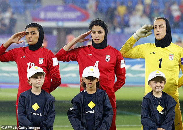 Iranian players, goalkeeper Raha Yazdani (right), Melika Motevalli (middle) and Fatemeh Amineh (left), salute during the national anthem before their match with the Philippines