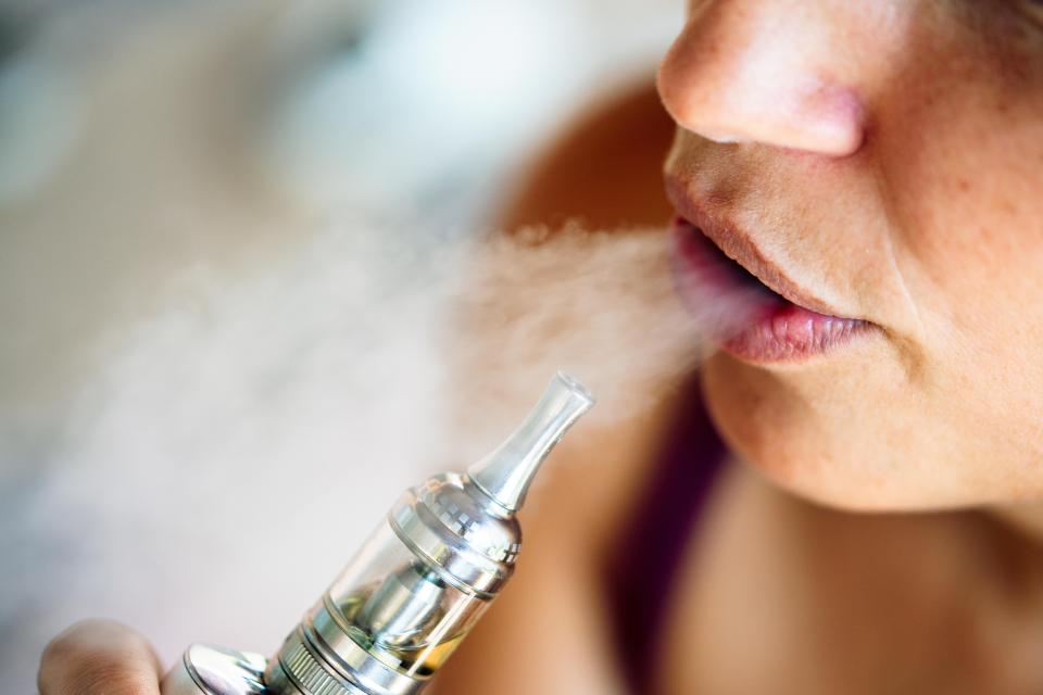 Close-up of a person exhaling vapor from an e-cigarette.