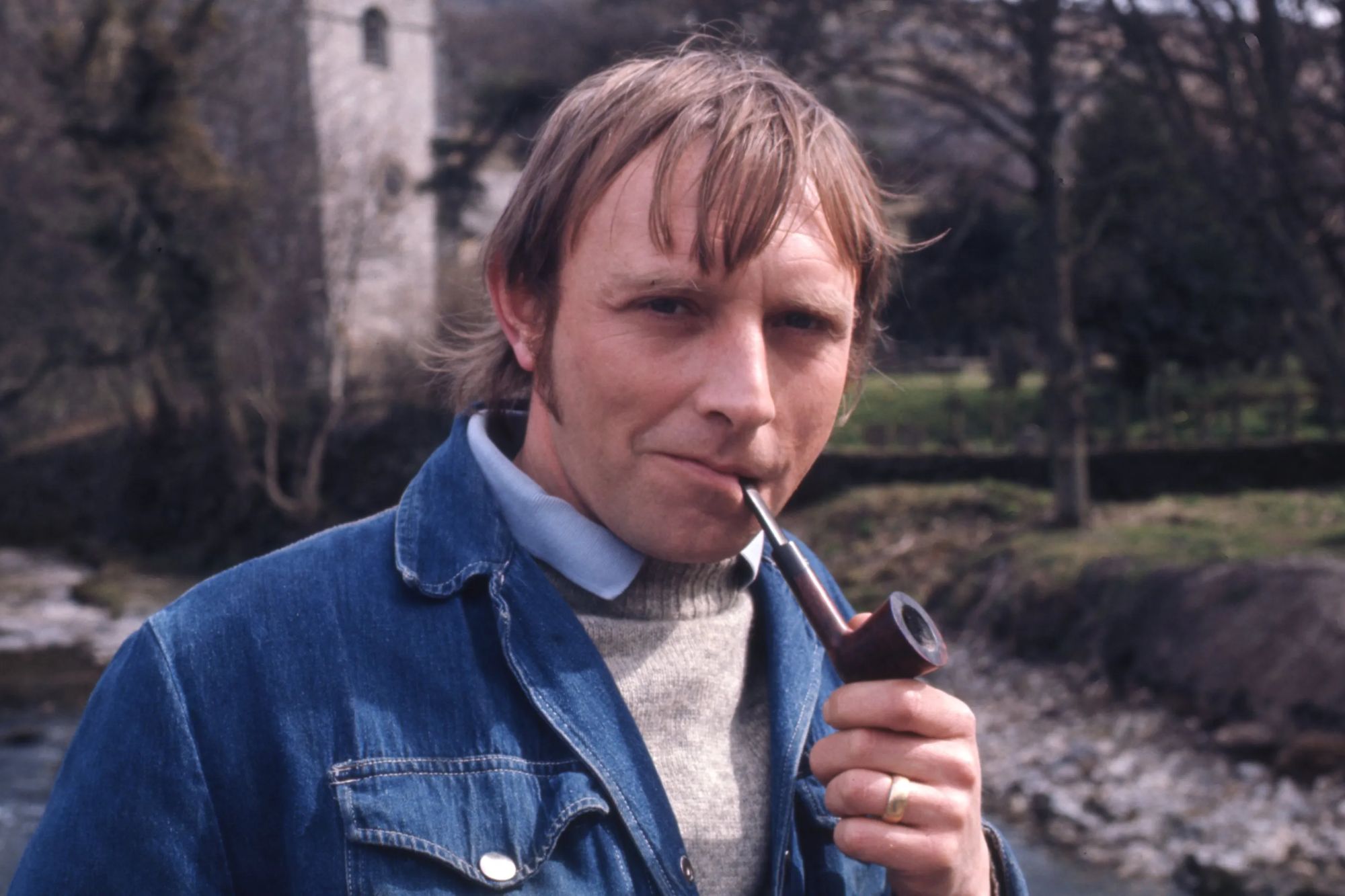 An image collage containing 1 images, Image 1 shows Eric Allan as Frank Blakey, holding a pipe