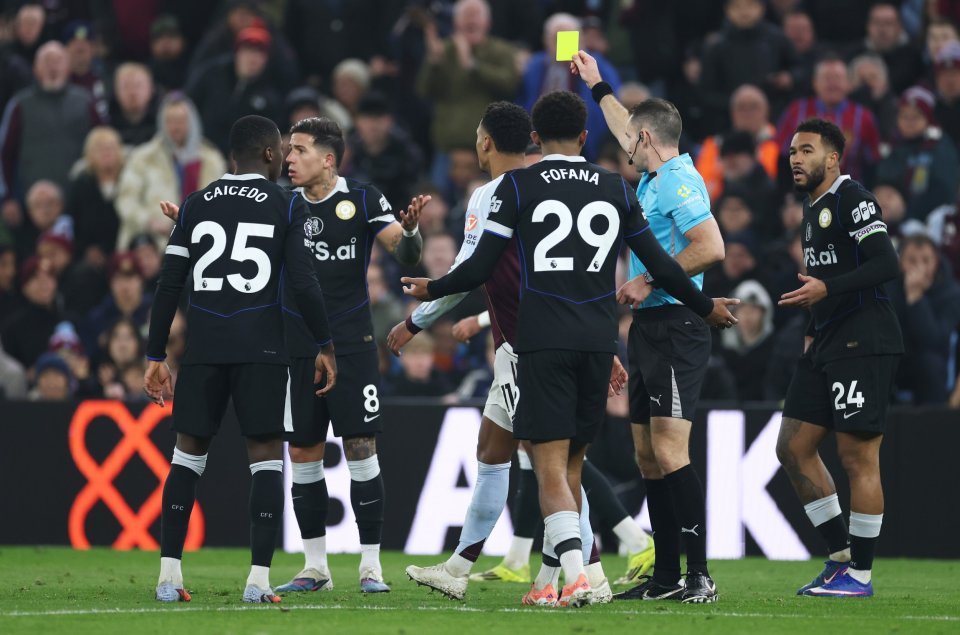 A soccer referee holds up a yellow card to a player during the Aston Villa v Chelsea Premier League match.