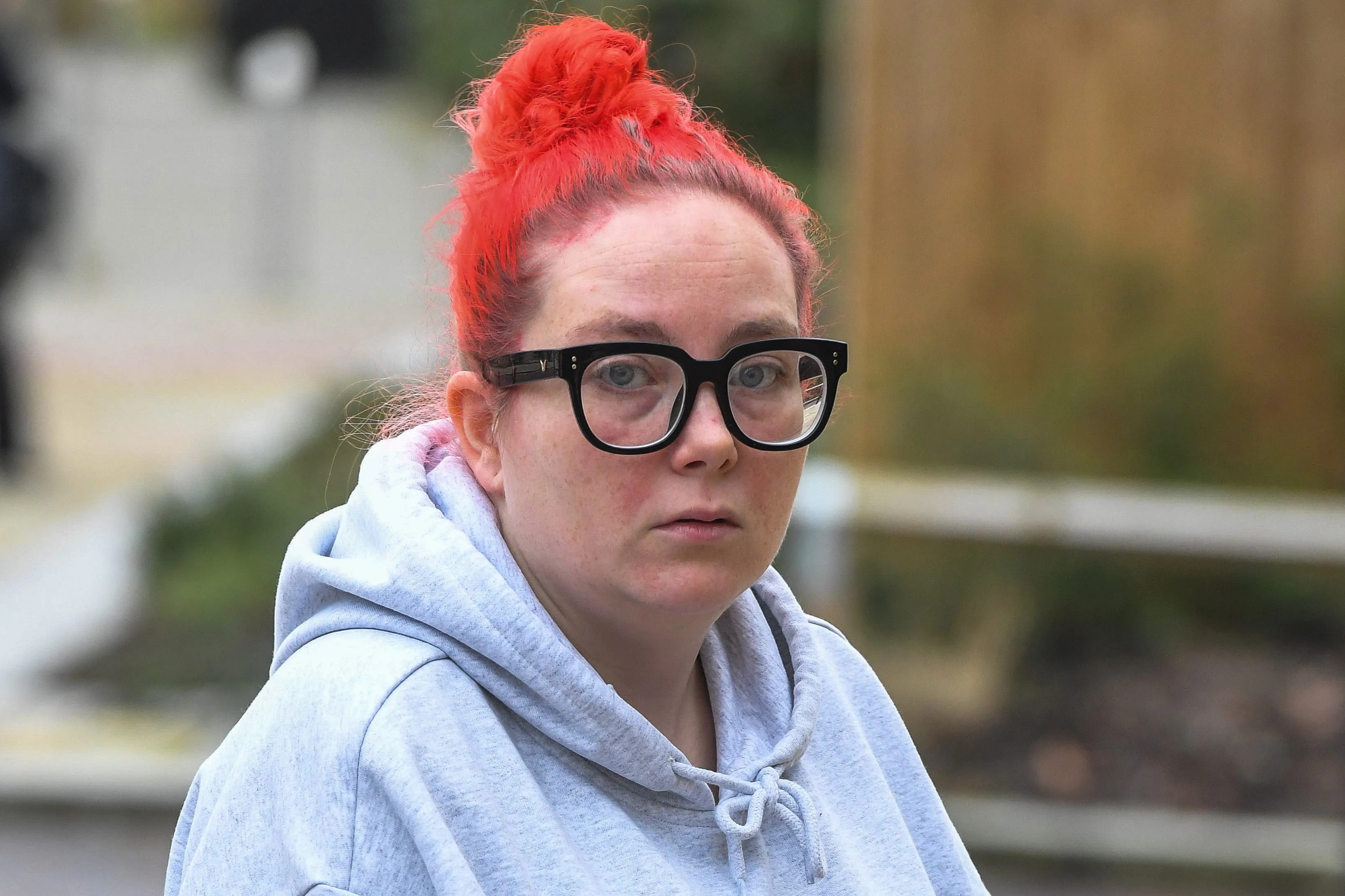 Stacey Sharples arriving at Bolton Crown Court, wearing a gray hoodie with a "VANS" logo and black-framed glasses, facing charges of perverting the course of justice.