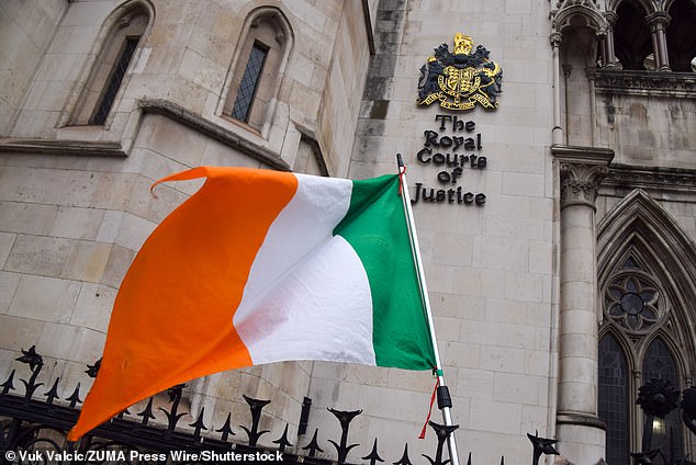 An Irish flag flies outside the Royal Courts of Justice in London as protesters gather