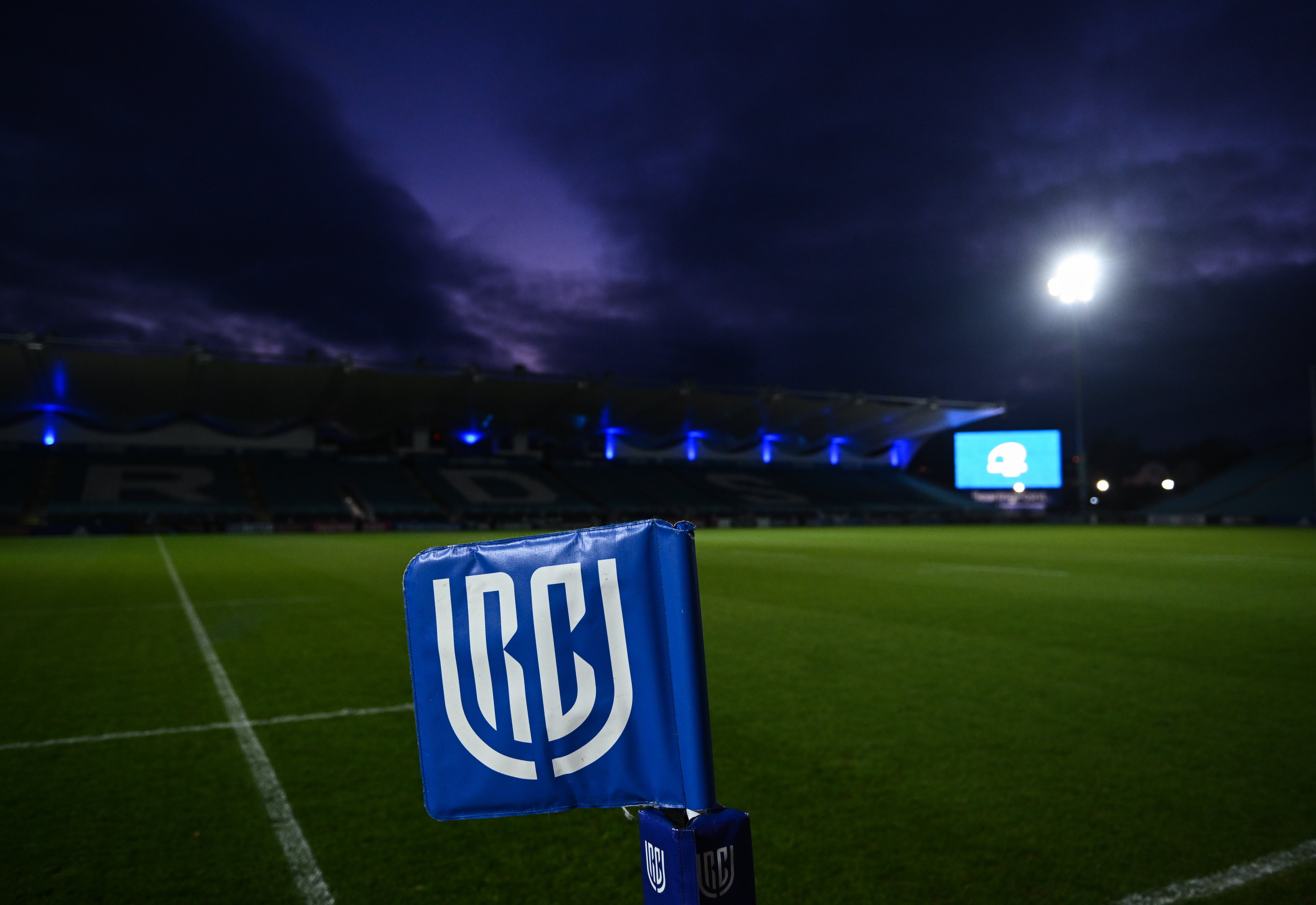 A corner flag with a white "URC" logo on a blue flag at the RDS Arena before a United Rugby Championship match.