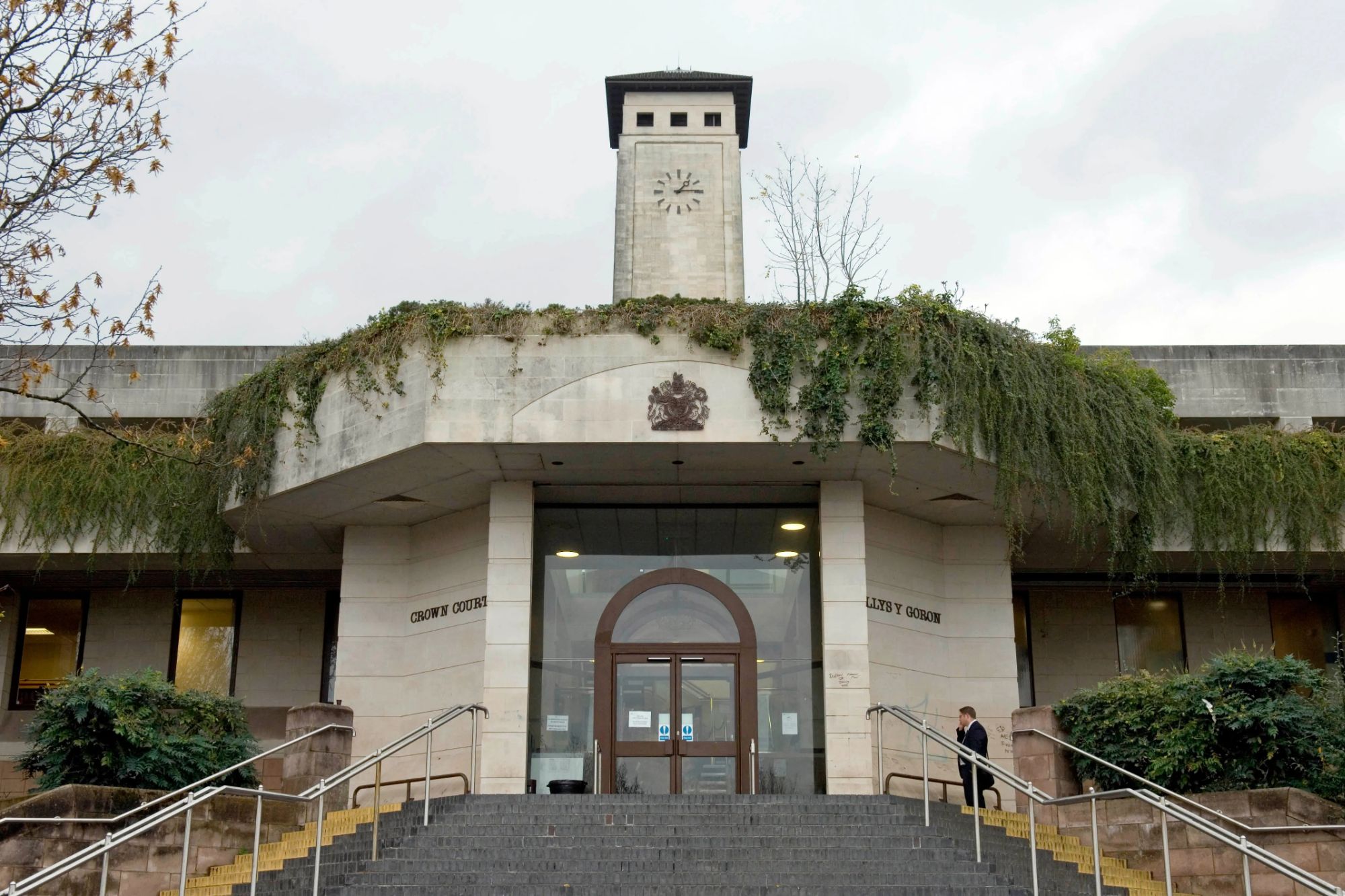 An image collage containing 1 images, Image 1 shows The exterior of Newport Crown Court in South Wales, featuring a man descending stone steps
