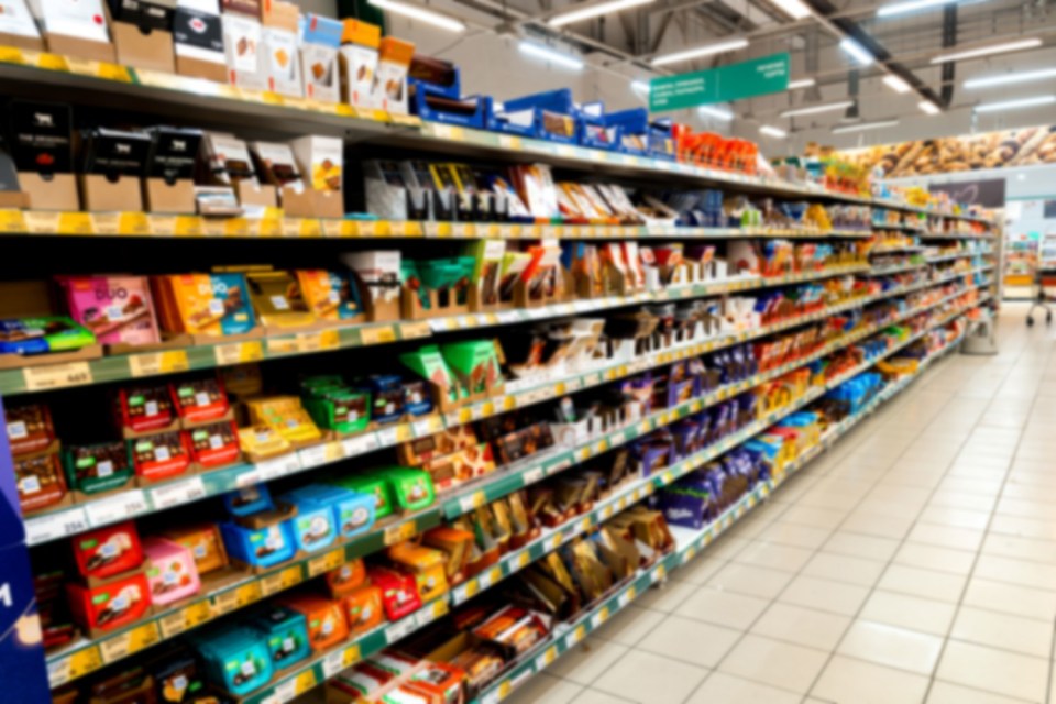 A blurred image of a grocery store aisle filled with various snack products.