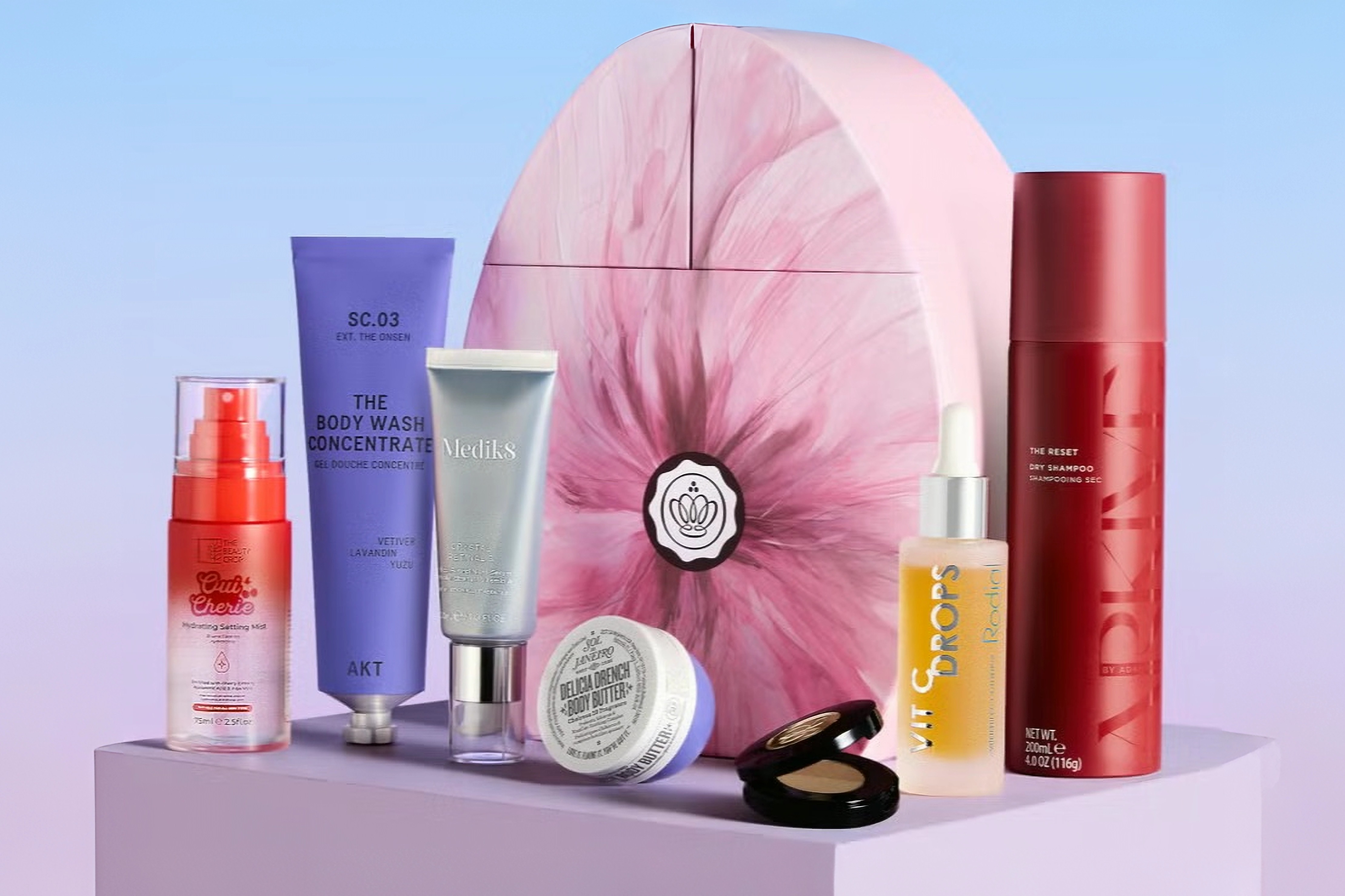 Beauty products and box packaging on a lavender surface.